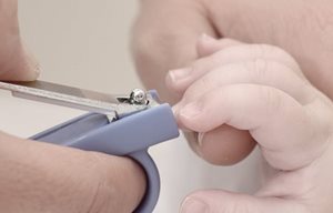 Una mujer cortándole las uñas a su bebé con un alicate de uñas.